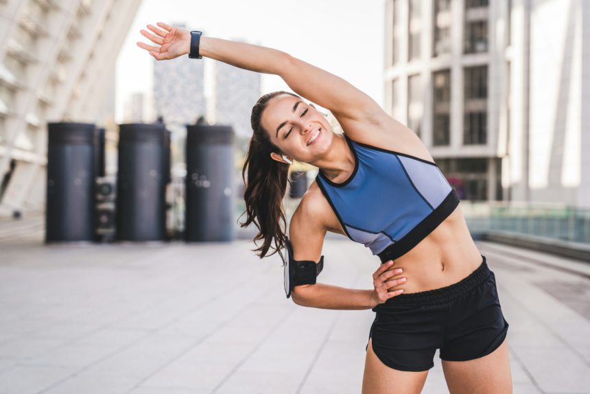 Beautiful caucasian girl exercising in fitness clothes in urban background