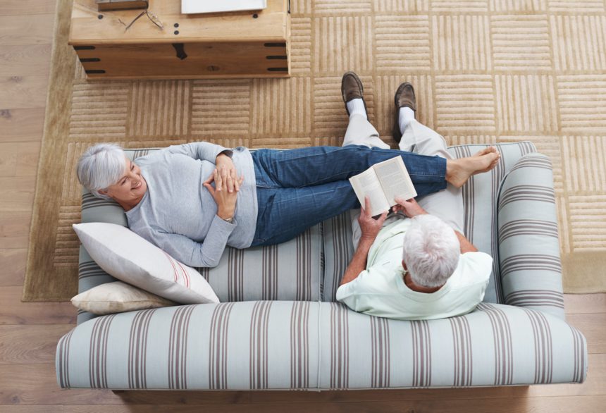 Poetry is the language of love...A senior man reading to his wife as she she lies on the couch.