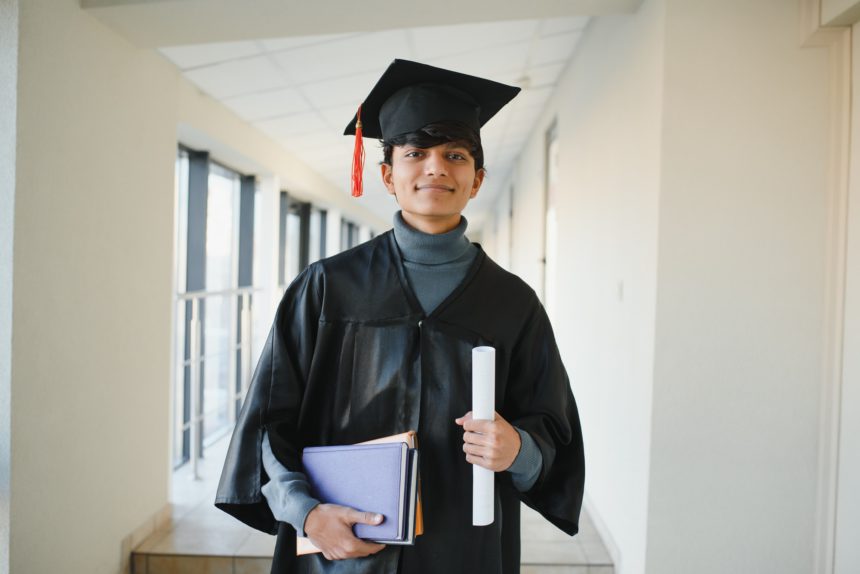 portrait of successful indian student in graduation gown.