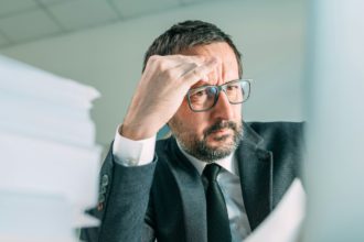 Serious business situation causing headache in office life, worried businessman looking at laptop