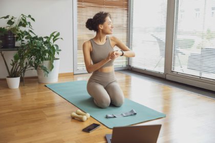 Smiling woman looking at sports watch and checking her performance after exercise at home